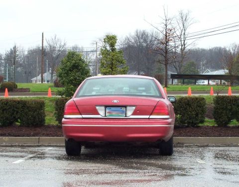 1998 Ford Crown Victoria - Rear view of a red 1998 Ford Crown Victoria parked in a lot on an overcast day.