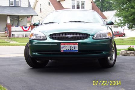 2000 Ford Taurus - The front of a green Ford Taurus is shown parked in a driveway with houses in the background.
