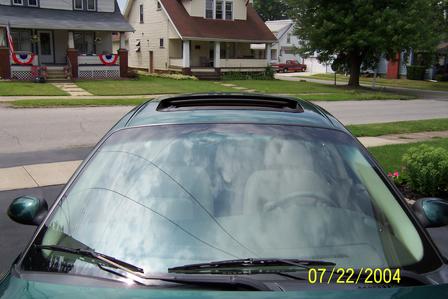 2000 Ford Taurus - The front view of a green sedan, showing the windshield and sunroof, with houses in the background.