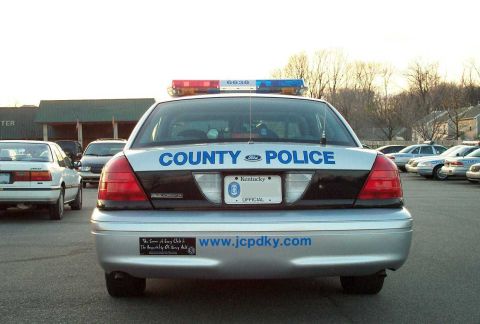 1998 Ford Crown Victoria - Rear view of a 1998 Ford Crown Victoria police car, showing 'COUNTY POLICE' text and a license plate.