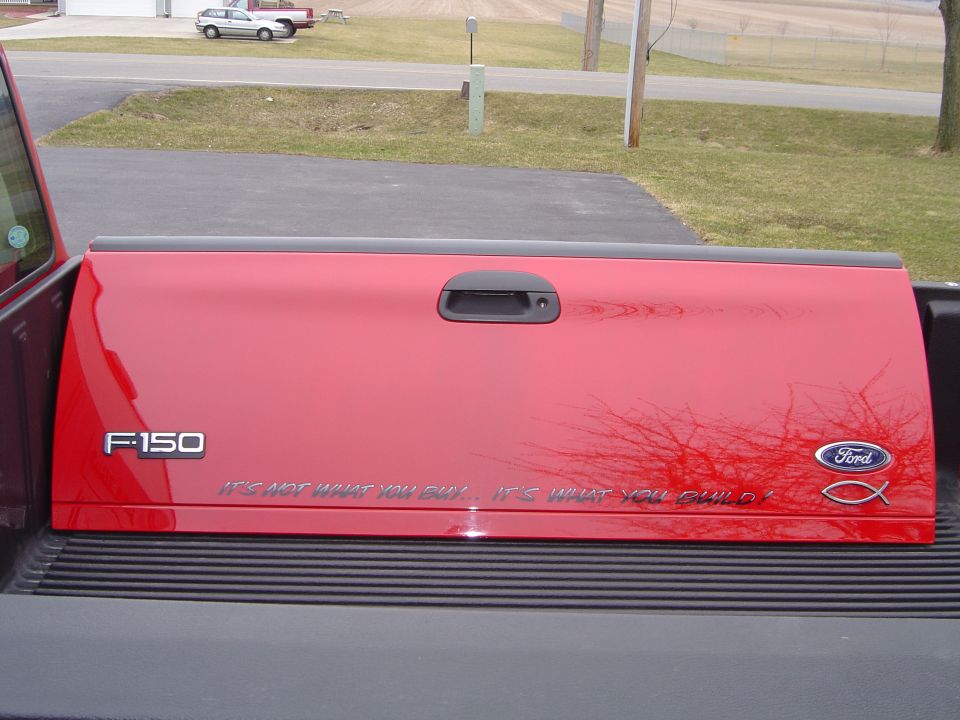 Red Ford F-150 tailgate with 'IT'S NOT WHAT YOU BUILD. IT'S WHAT YOU BUILD!' text and Ford logo
