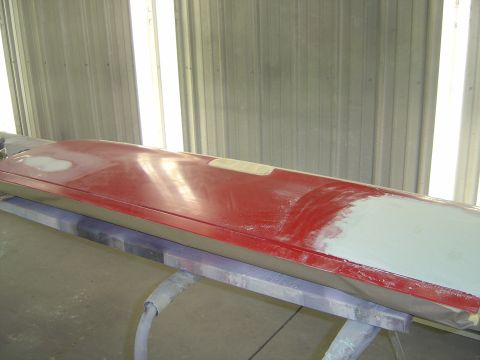 1978 Ford Bronco - A red vehicle door is undergoing bodywork in a workshop, with visible filler patches.