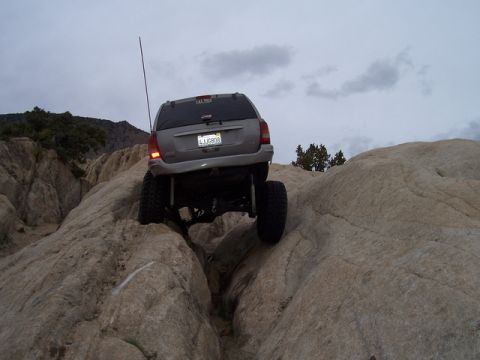 1989 Ford Bronco - A lifted Jeep Grand Cherokee tackles a challenging rocky terrain, its off-road capabilities.