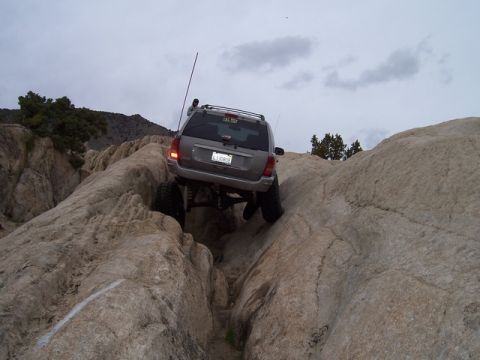 1989 Ford Bronco - An SUV is shown off-roading through a rocky terrain, demonstrating its capability on challenging surfaces.