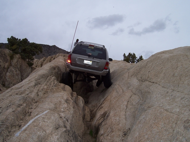 Gray SUV navigating a rocky trail, rear view