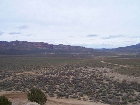 1989 Ford Bronco - A vast desert landscape stretches out towards distant mountains under a cloudy sky.
