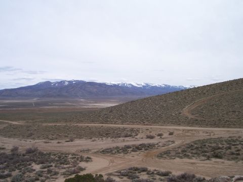 1989 Ford Bronco - A vast desert scene unfolds with snow-capped mountains on the horizon and winding dirt tracks below.