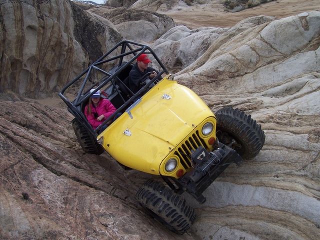 Yellow off-road vehicle with roll cage climbing rocks