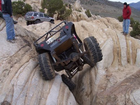 1989 Ford Bronco - A modified off-road vehicle navigates a steep, rocky incline with another SUV visible in the background.