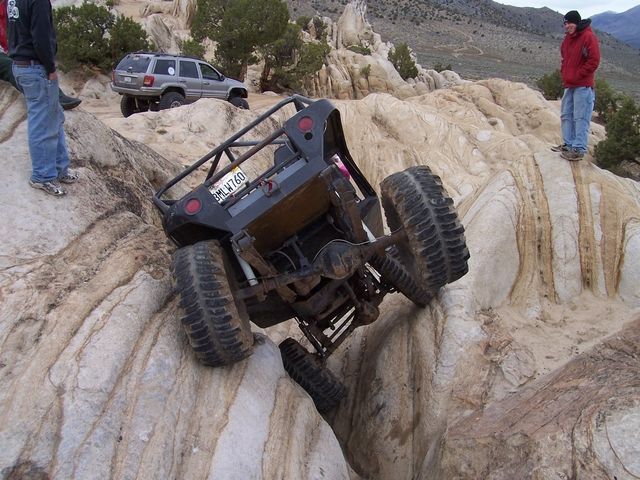 Off-road buggy tilted on rocks, another SUV in background