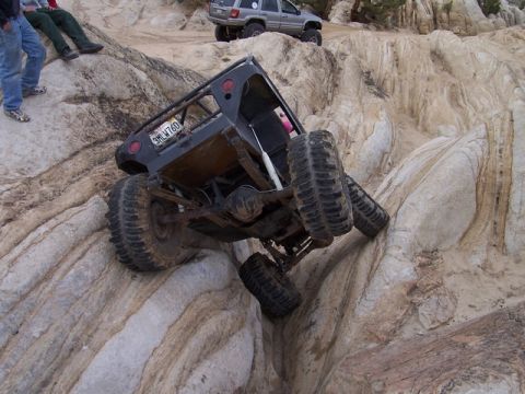 1989 Ford Bronco - An off-road vehicle navigates a steep, rocky incline with another SUV in the background.