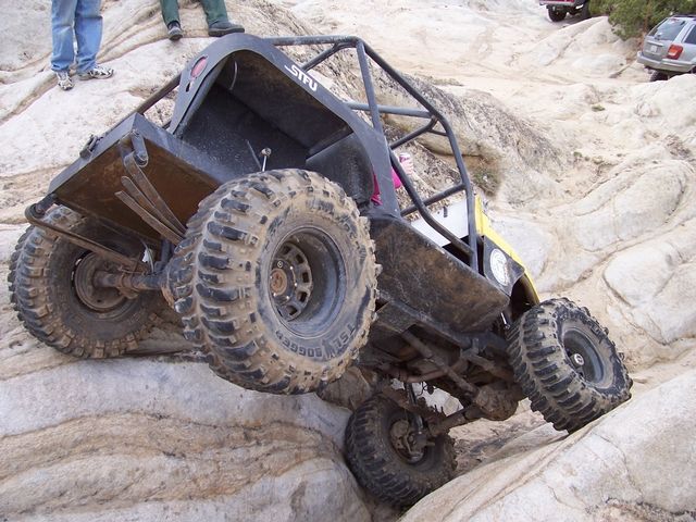 Tube-chassis rock buggy on Boggers flexed over slickrock with one wheel in the air