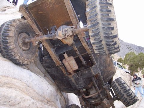 1989 Ford Bronco - An off-road vehicle navigates a rocky terrain, with another vehicle and a person observing.