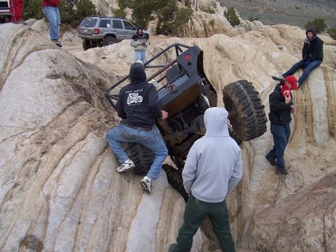1989 Ford Bronco - People gather around an off-road vehicle stuck on rocky terrain during an outing.