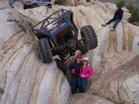 1989 Ford Bronco - A custom off-road buggy is precariously positioned on a rocky incline, with two people standing beneath it.