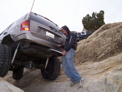 1989 Ford Bronco - Two Jeeps navigate a challenging rocky terrain, one requiring assistance with a jack.