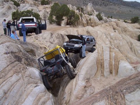 1989 Ford Bronco - Off-road vehicles tackle a challenging rocky landscape, with one Jeep Grand Cherokee having its hood open.
