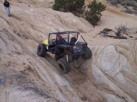 1989 Ford Bronco - An off-road buggy navigates a challenging rocky incline, its suspension and tire grip on the rough terrain.
