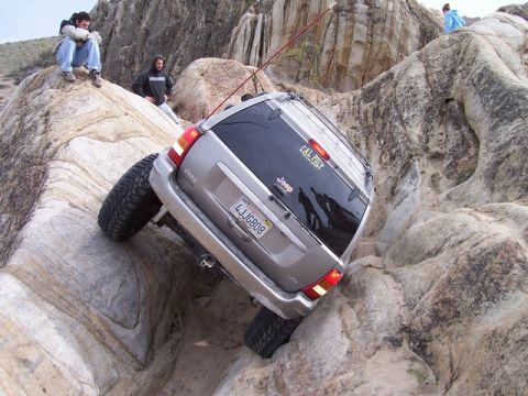 1989 Ford Bronco - Jeep Grand Cherokee attempting to climb over large rocks during an off-road excursion.