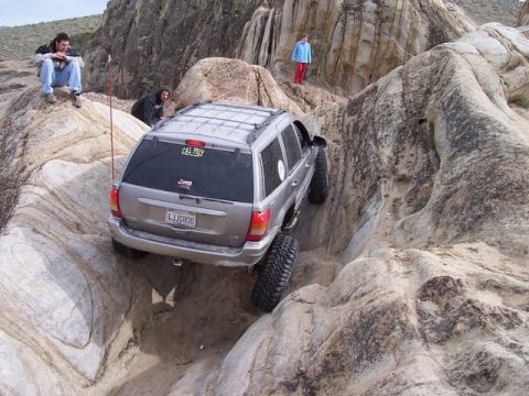1989 Ford Bronco - A Jeep Grand Cherokee tackles a challenging rocky terrain, demonstrating its off-road capabilities.