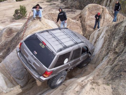 1989 Ford Bronco - A Jeep Grand Cherokee tackles a challenging rocky terrain during an off-road excursion.