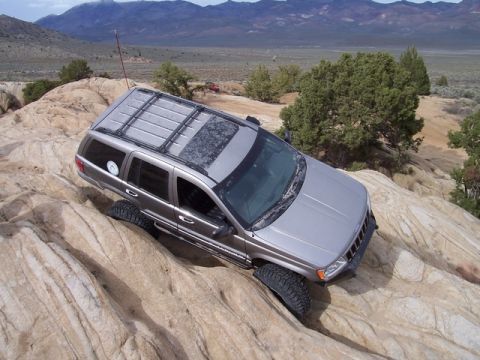 1989 Ford Bronco - A silver Jeep Grand Cherokee navigates a challenging rocky terrain during an off-road excursion.