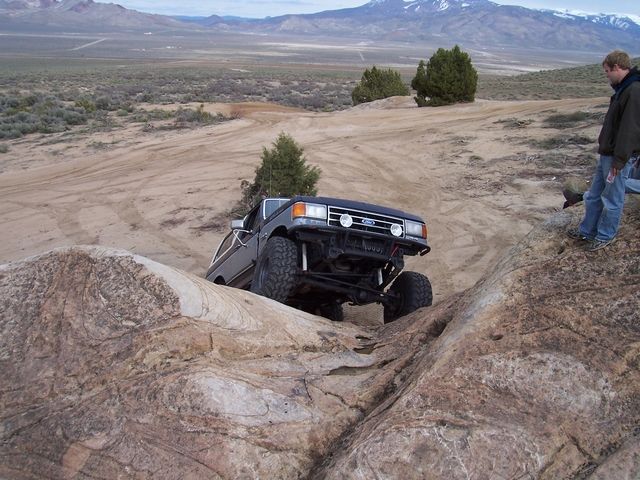 Dark-colored 1987 Ford Bronco climbing rocks