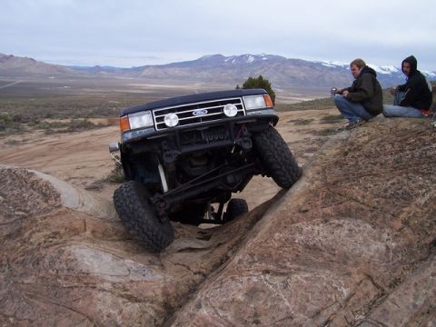 1989 Ford Bronco - 1989 Ford Bronco navigating a challenging rocky terrain with spectators observing.