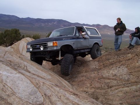 1989 Ford Bronco - A Ford Bronco navigates a rocky trail with two onlookers observing the action.