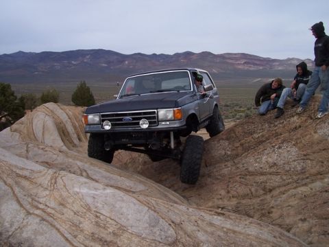 1989 Ford Bronco - A 1989 Ford Bronco navigates a rocky terrain with several onlookers observing the action.