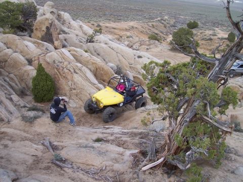 1989 Ford Bronco - Off-road buggy navigates a rocky incline with a photographer capturing the action.