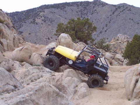 1989 Ford Bronco - This heavily modified off-road vehicle navigates a rocky desert terrain.