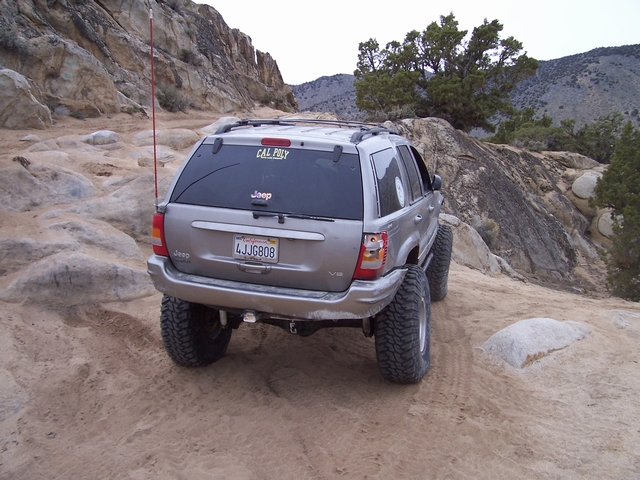Silver Jeep Grand Cherokee with lifted suspension and off-road tires on a rocky trail