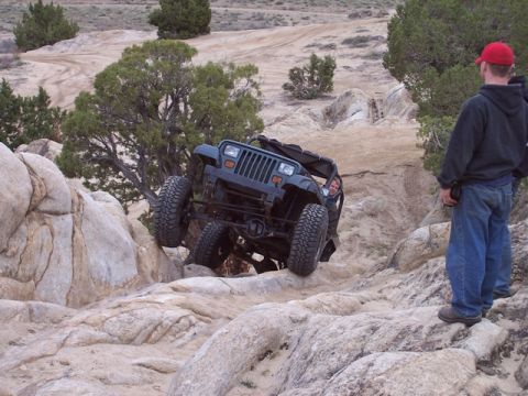 1989 Ford Bronco - A black Jeep Wrangler tackles a challenging rocky trail during an off-road excursion.