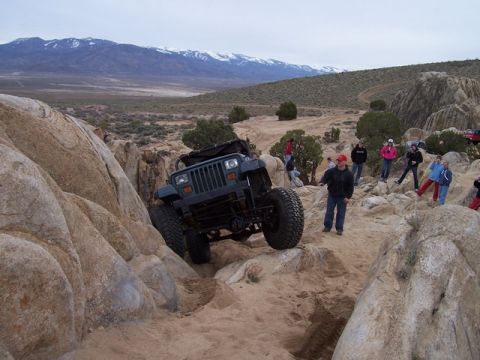 1989 Ford Bronco - A Jeep Wrangler navigates a challenging rocky trail with spectators observing the off-road action.