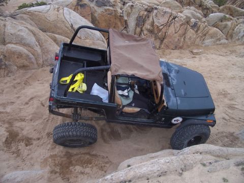 1989 Ford Bronco - A Jeep Wrangler navigates a sandy, rocky off-road trail.