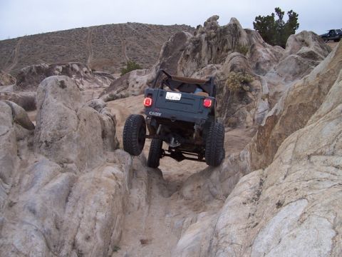 1989 Ford Bronco - Off-road vehicle maneuvers through a rocky trail with another vehicle in the distance.