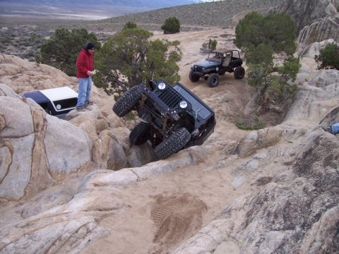 1989 Ford Bronco - Off-road vehicles navigate a challenging rocky terrain, with one Jeep dramatically tilted on its side.