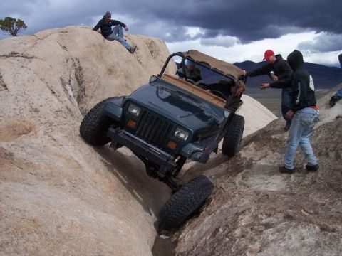 1989 Ford Bronco - Jeep Wrangler navigating a challenging rocky terrain with onlookers present.