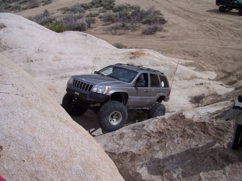 1989 Ford Bronco - A modified Jeep Grand Cherokee tackles a challenging rocky trail during an off-road excursion.