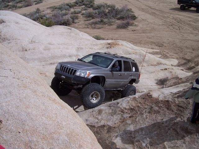 Gray Jeep Grand Cherokee with lifted suspension navigating rocky terrain