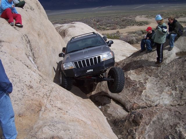 Gray Jeep Grand Cherokee with custom bumper off-roading on rocks