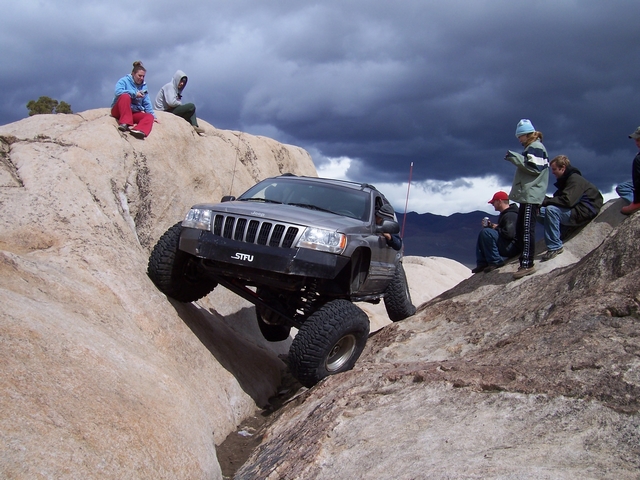 Jeep Grand Cherokee climbing rocks with people watching