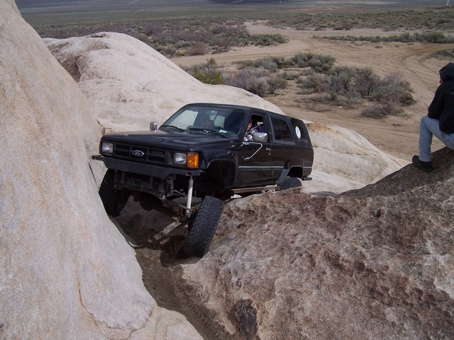 Black SUV navigating a rocky trail. Driver visible inside