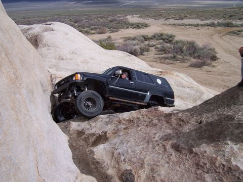 1989 Ford Bronco - This black SUV is shown off-roading on a rocky terrain, with a person visible inside.
