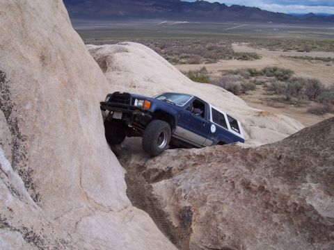 1989 Ford Bronco - An off-road SUV navigates a challenging rocky terrain in a desert environment.