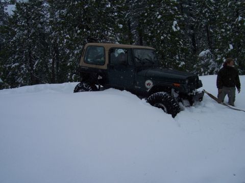 1989 Ford Bronco - Jeep Wrangler deep in snow with a person standing nearby.