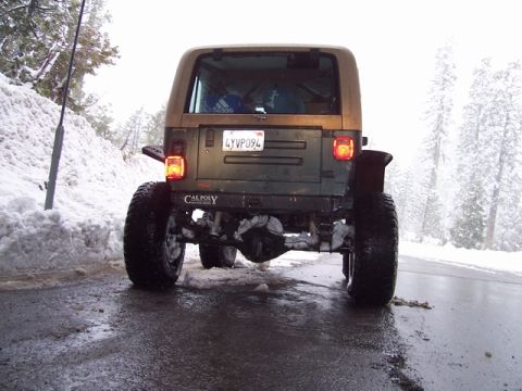 1989 Ford Bronco - A lifted Jeep Wrangler navigates a wet, snowy road during winter conditions.