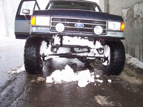 1989 Ford Bronco - This lifted Ford truck is seen in the snow, with its front grille and headlights clearly visible.