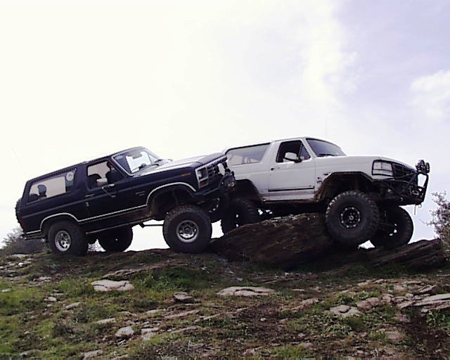 Dark and white lifted Ford Broncos on a rocky dirt mound outdoors